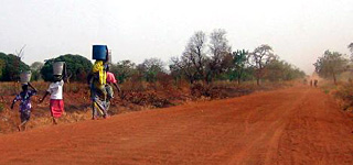 Photograph of women carrying water alongside a road. Photograph of women carrying water alongside a road.