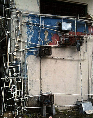 A network of pipes crisscross the outside of a building. A network of pipes crisscross the outside of a building.