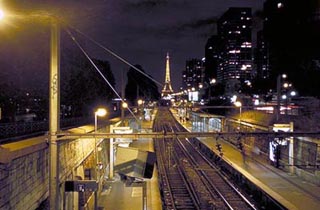 A photo of the Paris Metro tracks heading off to a lit Eiffel Tower on the horizon. A photo of the Paris Metro tracks heading off to a lit Eiffel Tower on the horizon.