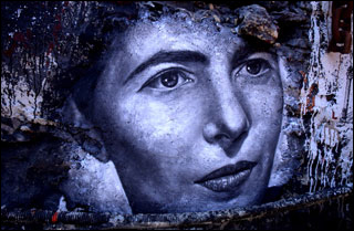 A black and white mural of a woman's face, with large eyes, a pointed nose, and thin lips, closed in a serious expression. A black and white mural of a woman's face, with large eyes, a pointed nose, and thin lips, closed in a serious expression.