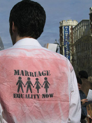 The back of of a man's shirt featuring stencils of two same-sex couples and the message Marriage Equality Now. The back of of a man's shirt featuring stencils of two same-sex couples and the message Marriage Equality Now.