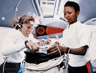 Two female astronauts work on an experiment onboard a space shuttle. Two female astronauts work on an experiment onboard a space shuttle.
