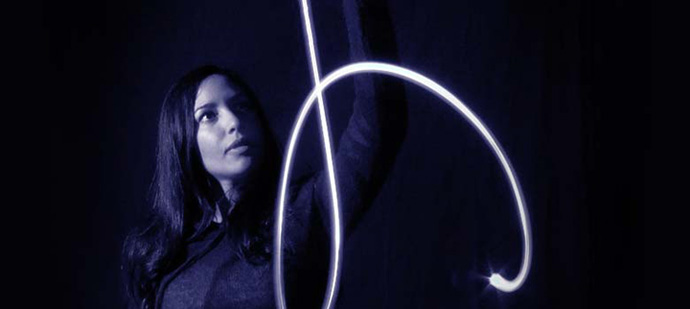 A photo of a woman and a beam of blue light in the dark. A photo of a woman and a beam of blue light in the dark.