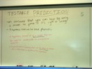 Notes on a whilteboard explain testable predictions.