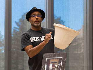 A man holds a bell-shaped ceramic water filter up for display. A man holds a bell-shaped ceramic water filter up for display.