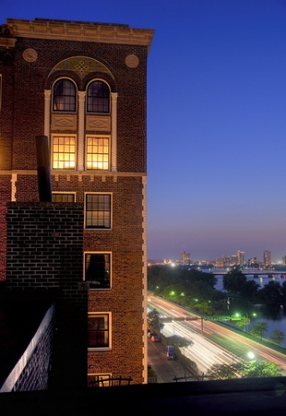 Photograph of a brick building against a deep blue sky, with the city visible in the background. Photograph of a brick building against a deep blue sky, with the city visible in the background.