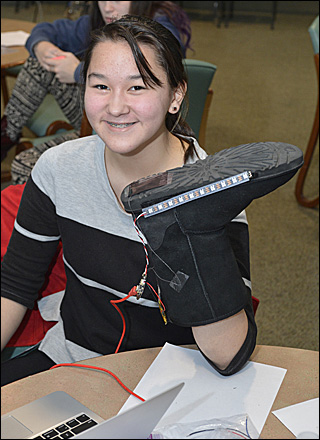 A girl holds up a boot that she is adding lights to. A girl holds up a boot that she is adding lights to.